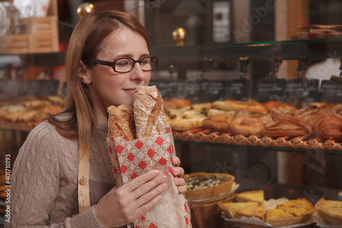 Photos Mature female baer enjoying smelling freshly baked bread at her bakery store