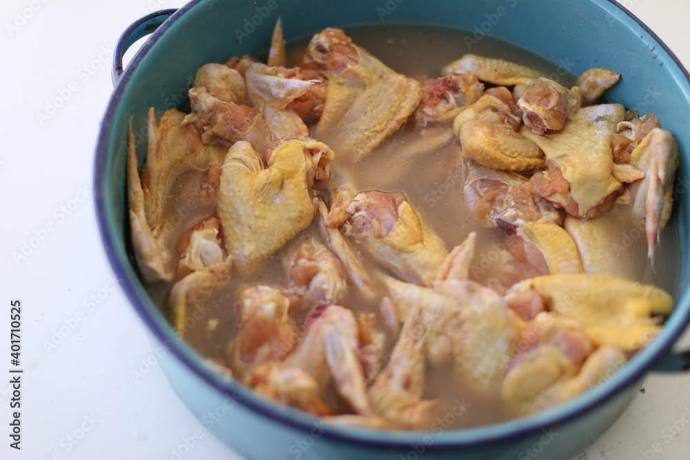 Alitas de pollo crudas, alitas asandose, en casuela azul, comida