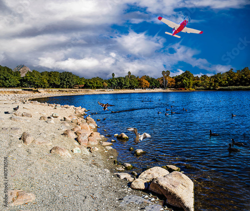 Beautiful single engine plane taking off from Brackett airport climbing over Puddingstone lake Ca. landscape. photo