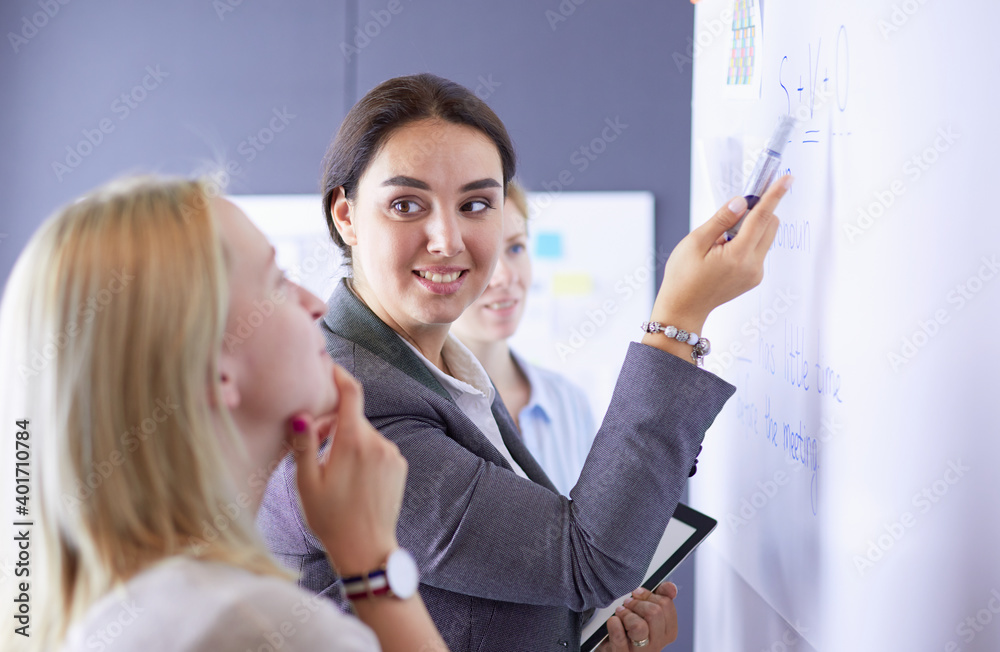 Business, education and office concept - business team with flip board in office discussing something.