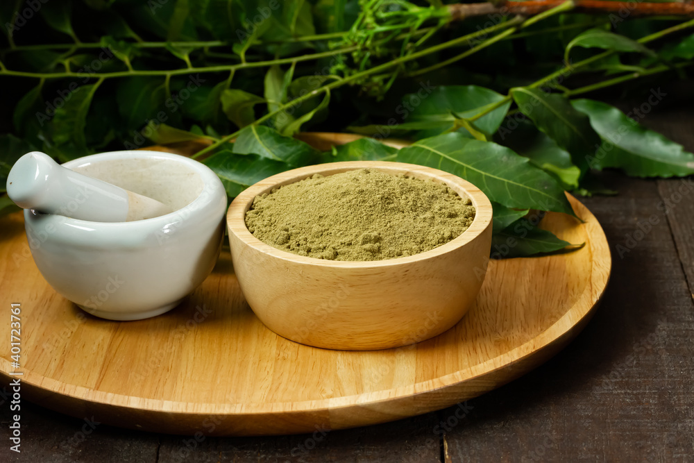 neem powder in wooden bowl with neem leaf and white mortar and pestle on wooden background. neem powder in wooden bowl with neem leaf and white mortar and pestle on wooden background.