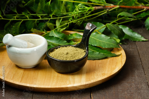 Foto neem powder in black bowl with neem leaf and white mortar and pestle on wooden background