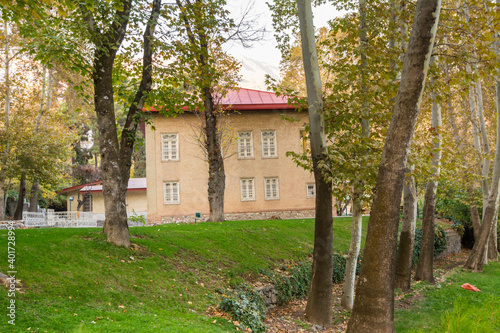 Historic building hidden in the golden forest in autumn with background of mountain in Sa'dabad palace Complex, built by the Qajar and Pahlavi monarchs, located in Shemiran, Greater Tehran, Iran photo