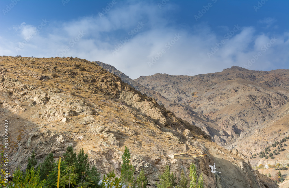 Tochal mountain ridge with rocks and trees in autumn against blue sky, Tehran, Iran. Tochal is a popular recreational region for Tehran's residents