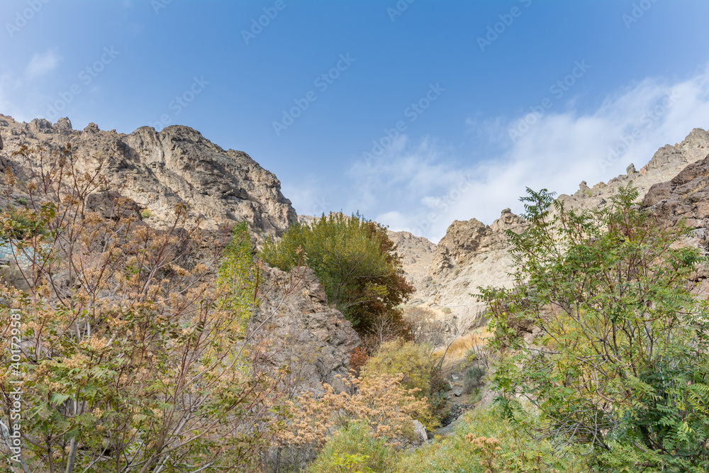 Tochal mountain ridge with rocks and trees in autumn against blue sky, Tehran, Iran. Tochal is a popular recreational region for Tehran's residents