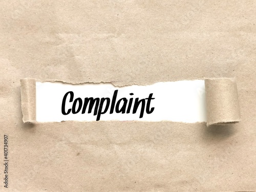Phrase 'Complaint' appearing behind torn brown paper. For background purpose.