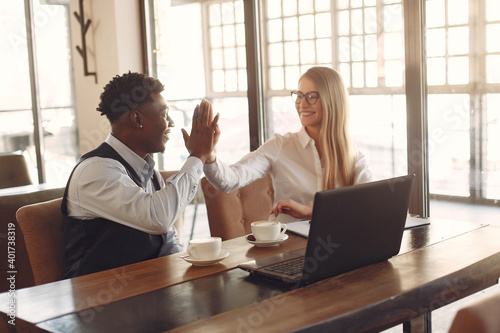 Handsome black man in a blue shirt. Businessman working in a cafe. Woman with her business partner.