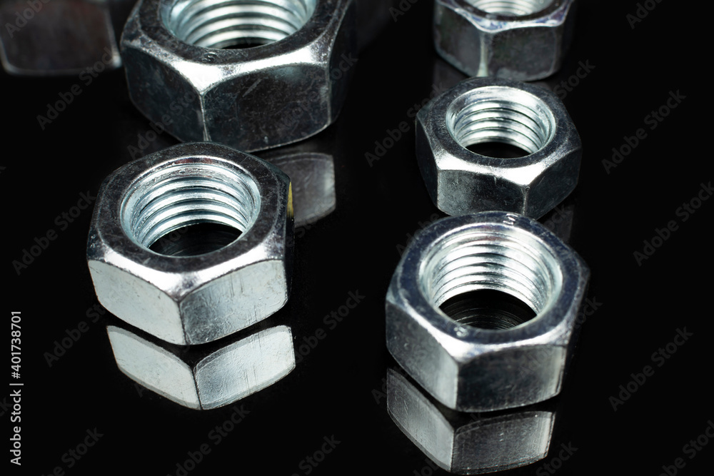 several large metal nuts on a black background several large metal nuts on a black background