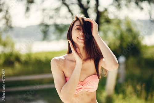 Girl near a lake. Woman in a stylish swimsuits. Lady on a summer vacation