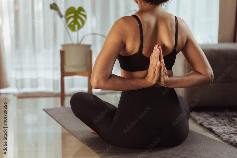 Young woman practicing yoga at home. Fit woman in sportwear doing yoga online at home in living room.