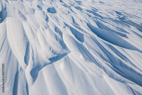 Snow texture. Wind sculpted patterns on snow surface. Wind in the tundra and in the mountains on the surface of the snow sculpts patterns and ridges (sastrugi). Arctic, Polar region. Winter background photo