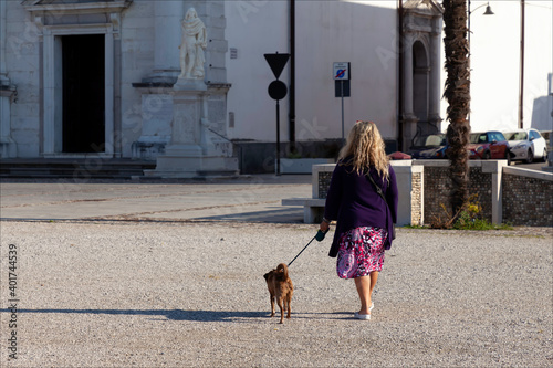 Donna che porta a passeggio il cane in centro storico della città.