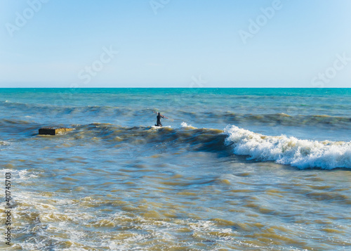 A man in a black wetsuit on the surf of the Black Sea Sochi 05.12.2019 © jockermax3d