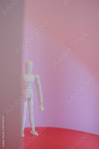 wooden man stands on a red and pink background