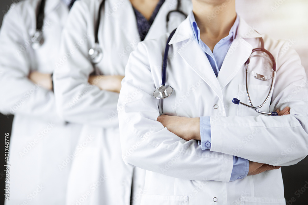 Group of modern doctors standing as a team with arms crossed in sunny hospital and ready to help patients. Medical help, insurance in health care Group of modern doctors standing as a team with arms crossed in sunny hospital and ready to help patients. Medical help, insurance in health care