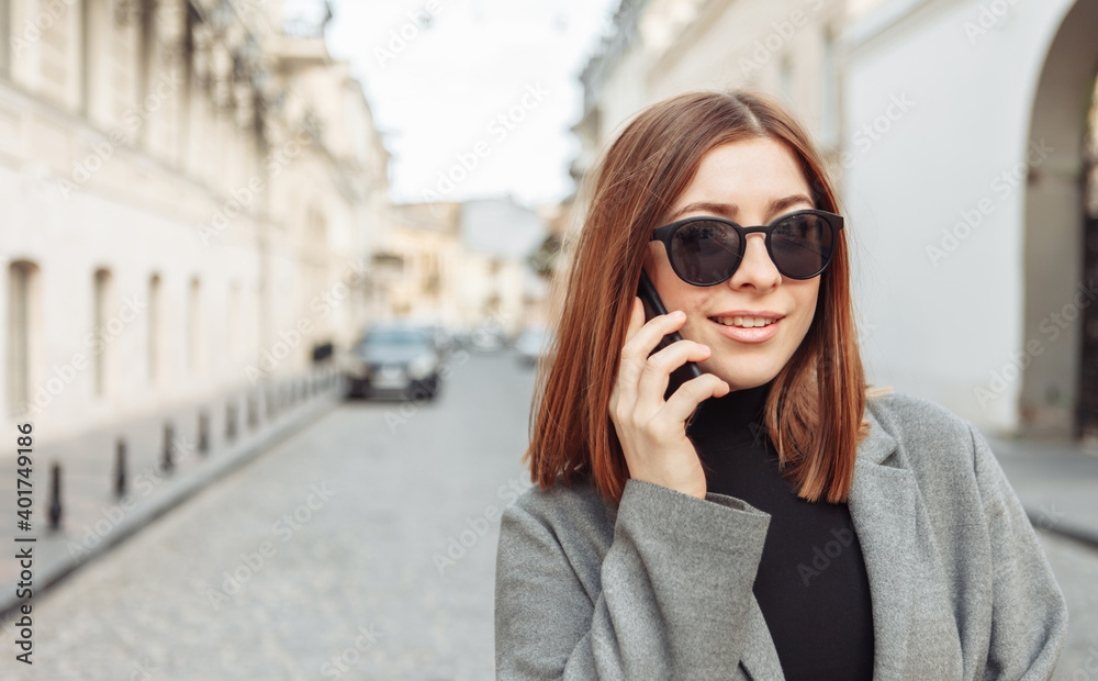 Portrait of a cute woman with straight hair and sunglasses talking on the phone in the city