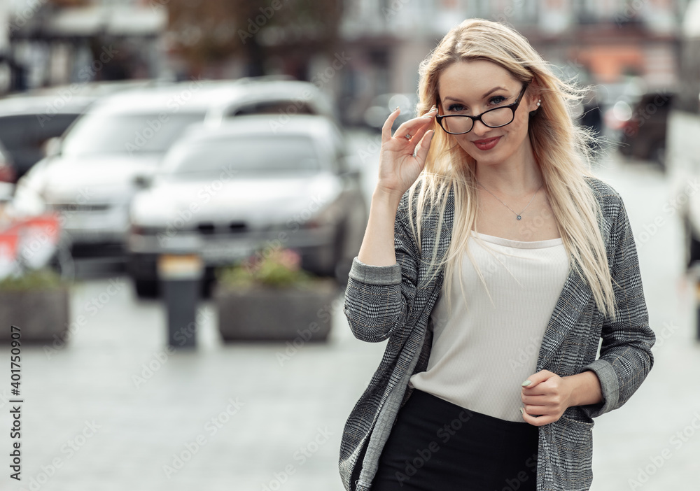 Portrait of a business woman in the city. Young blonde girl in business clothes