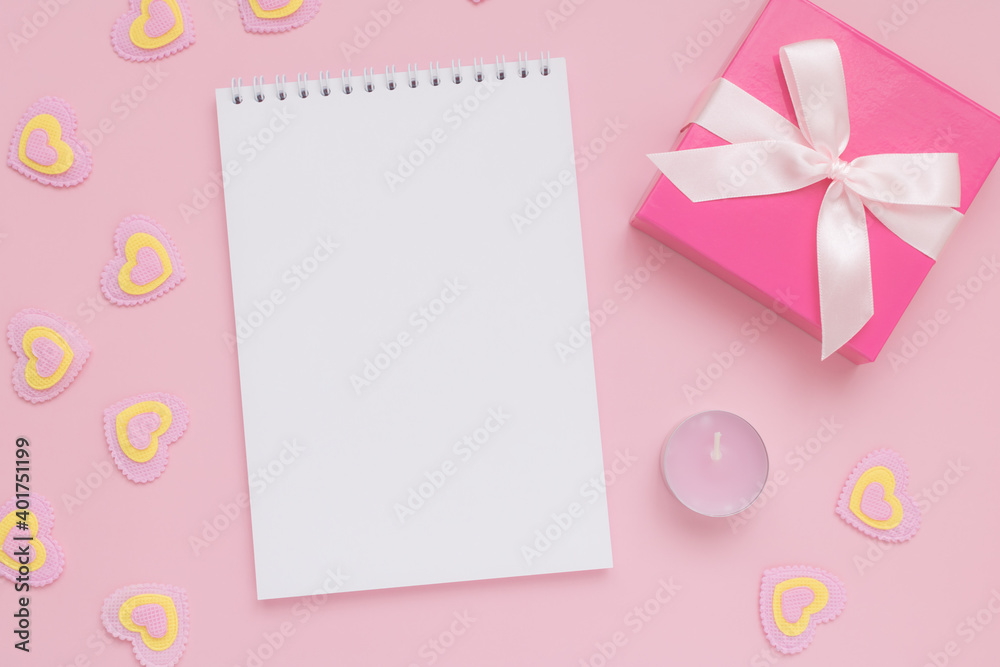 White blank notepad sheet, pink candle, gift box and pink and yellow hearts on pink background, Happy Valentine's Day