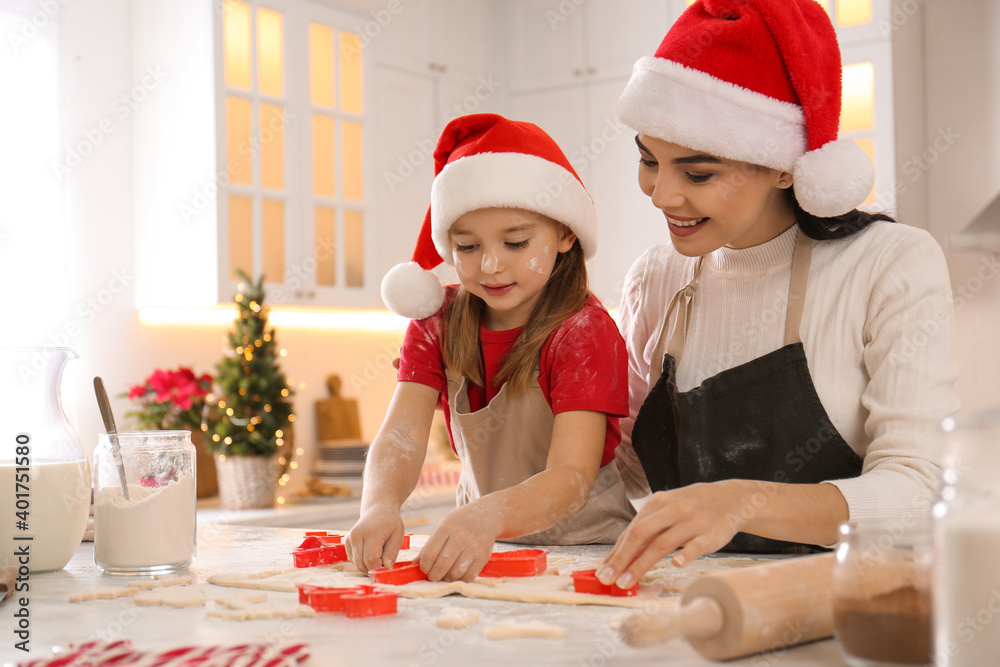 Mother with her cute little daughter making Christmas cookies in kitchen