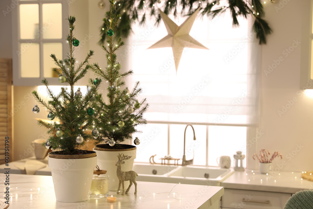 Small Christmas trees decorated with baubles and festive lights in kitchen Small Christmas trees decorated with baubles and festive lights in kitchen