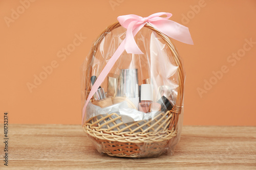 Wicker gift basket with cosmetic products on wooden table photo