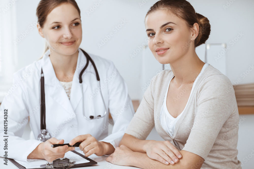 Doctor and patient are sitting and discussing health examination results in clinic office. Health care, medicine and good news concepts Doctor and patient are sitting and discussing health examination results in clinic office. Health care, medicine and good news concepts