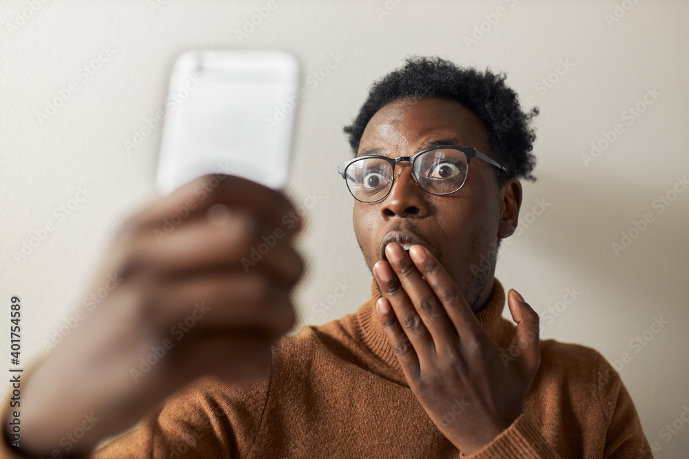 Isolated shot of funny emotional young black guy widening eyes and covering  mouth with hand, expressing surprise while chatting online using front  camera for video call, receiving shocking news Stock Photo |