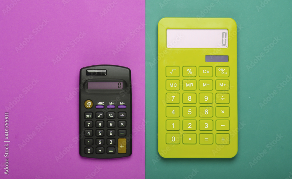 Two calculators on a purple-green background. Top view. Two calculators on a purple-green background. Top view.