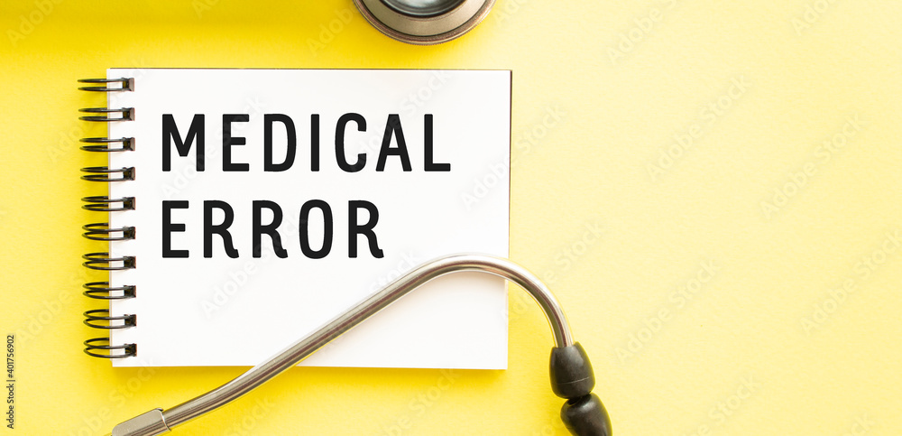 Text MEDICAL ERROR on notebook with stethoscope on yellow background. Text MEDICAL ERROR on notebook with stethoscope on yellow background.
