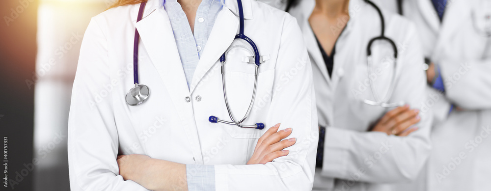 Group of professional doctors is standing as a team with arms crossed in sunny clinic. Medicine concept during Coronavirus pandemic. Covid-2019 Group of professional doctors is standing as a team with arms crossed in sunny clinic. Medicine concept during Coronavirus pandemic. Covid-2019
