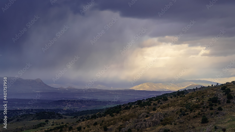Dramatic storm sky landscape with sun rays between the clouds and over the mountains. Dark landscape.

