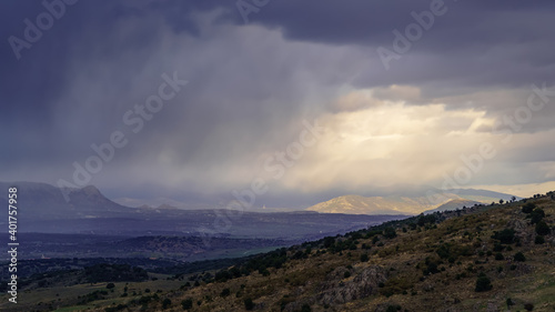 Dramatic storm sky landscape with sun rays between the clouds and over the mountains. Dark landscape. 