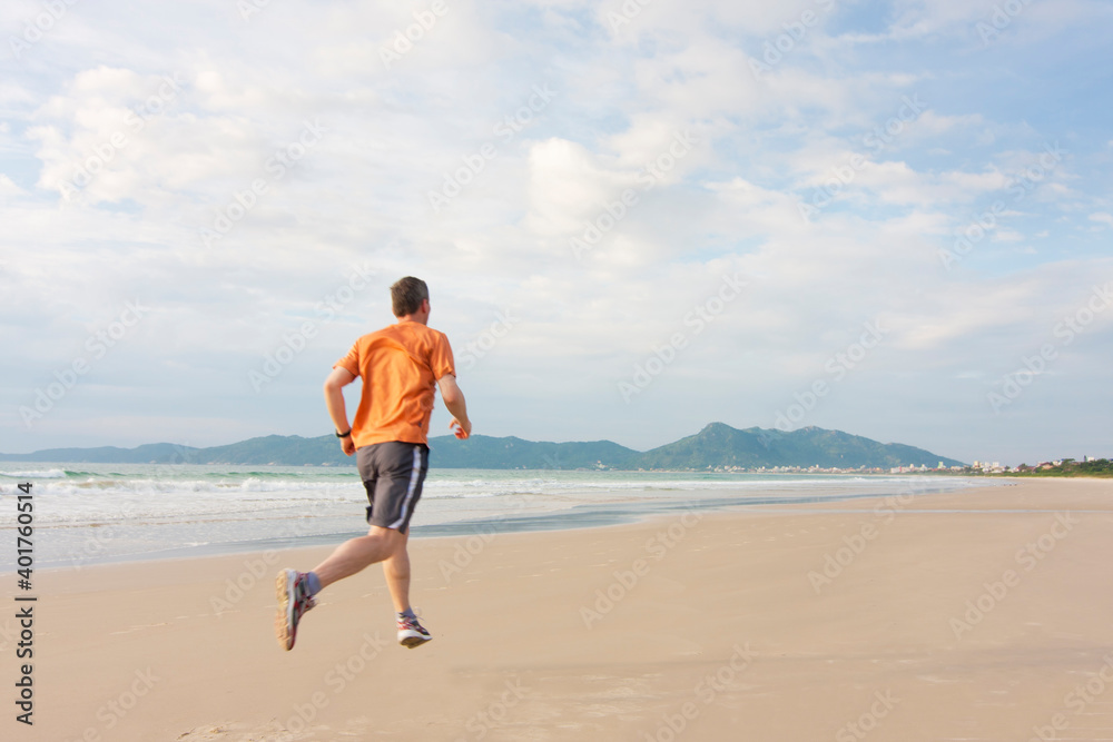 Mature man running on a long beach early in the morning