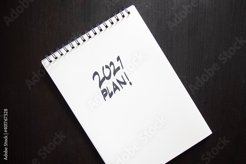 2021 plan notepad list concept, handwriting notepad. Inscription "2021 Plan" in white paper and "focus!, target!,money!" in notepad, close up, top view, concept of planning, goal setting. 