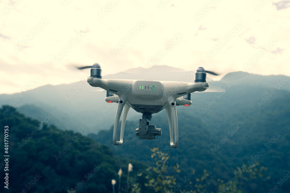 Fototapeta premium White drone with camera flying in spring mountains
