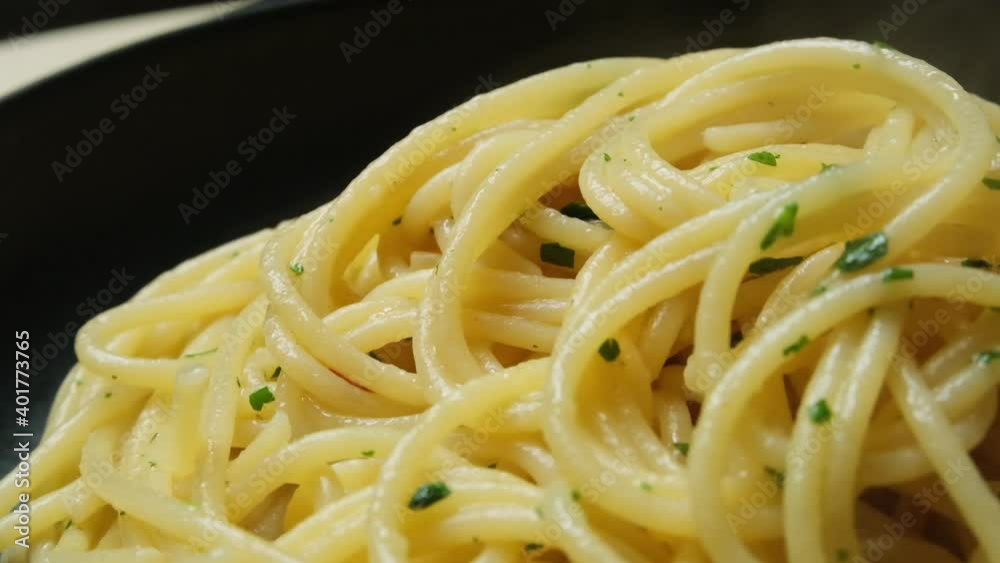 Delicious food pasta hot spaghetti with olive oil and parsley in a black plate. slow motion, rotation. Italian cuisine recipe Delicious food pasta hot spaghetti with olive oil and parsley in a black plate. slow motion, rotation. Italian cuisine recipe