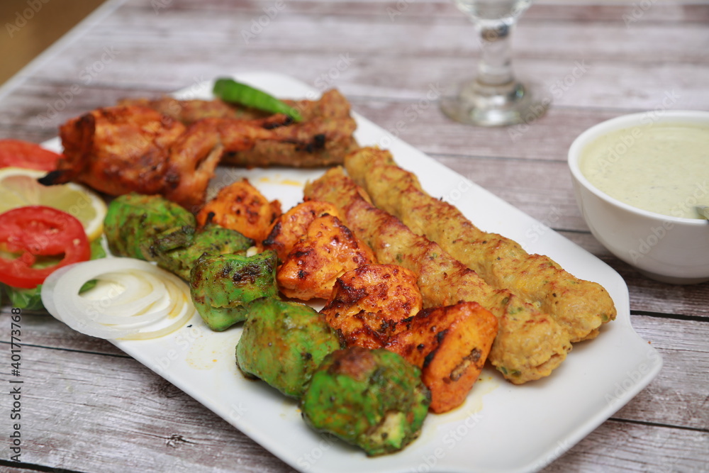 Mix Kebab skewers Served with mint sauce wooden background with glass of water Mix Kebab skewers Served with mint sauce wooden background with glass of water