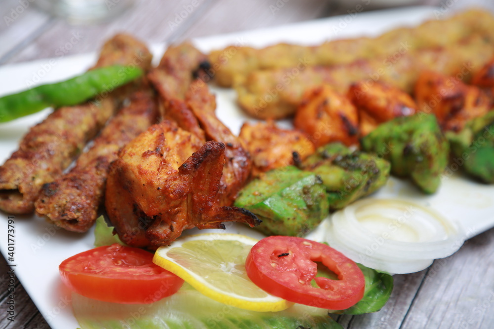 Mix Kebab skewers Served with mint sauce wooden background with glass of water Mix Kebab skewers Served with mint sauce wooden background with glass of water