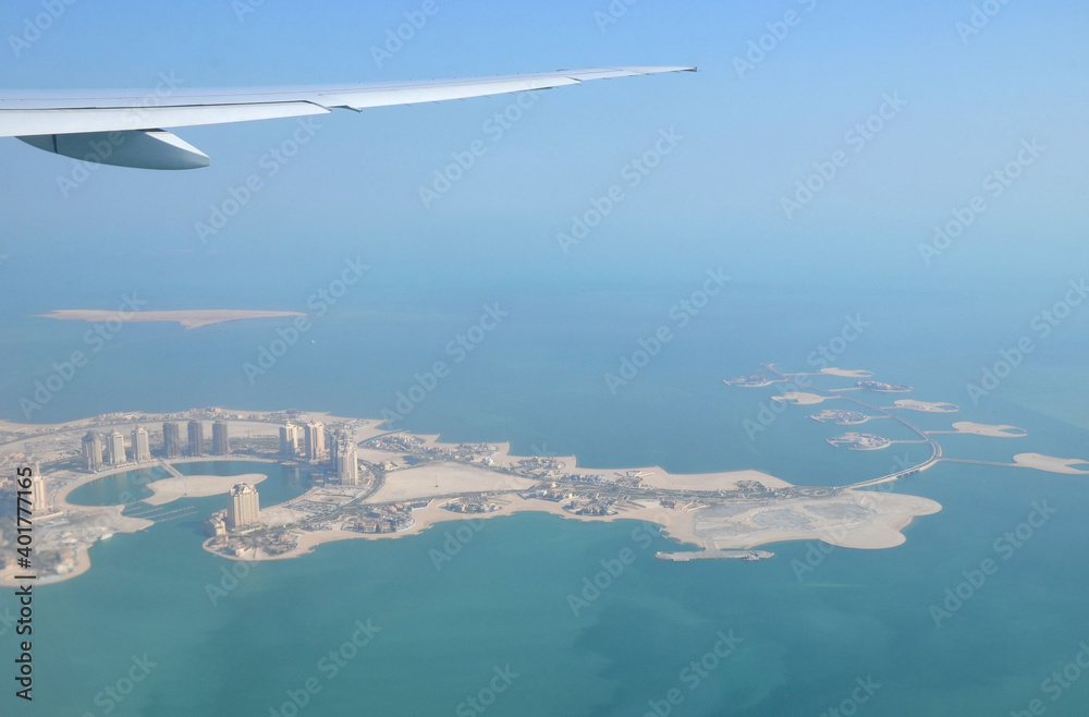 Naklejka premium The Pearl-Qatar island in Doha through the airplane porthole, aerial view