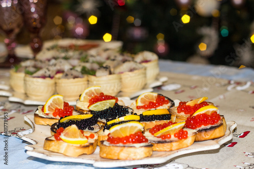 Caviar sandwiches decorated with lemon on the Christmas table. Treats on the festive table. A delicacy treat for Christmas and New Years. Flat layout. Top view. Close-up.