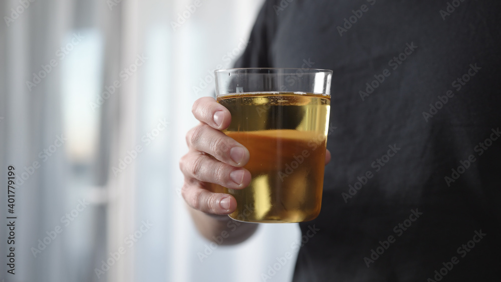 Man hold and drink apple cider in tumbler glass in front of window Man hold and drink apple cider in tumbler glass in front of window