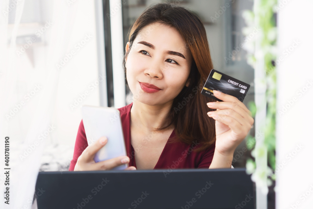 Asian woman hand holding credit card and mobile phone dreaming to buy something Asian woman hand holding credit card and mobile phone dreaming to buy something
