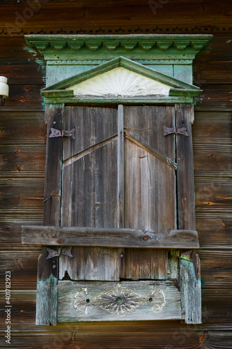 An old window in an abandoned traditional house in a Russian village. Wooden window with boarded-up shutters and traditional Russian patterns