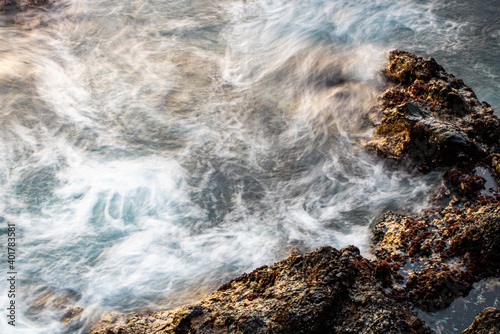 Sunset seascape with sea water in motion blur  stones on the beach. Atlantic ocean  Tenerife island. Long exposure. Background