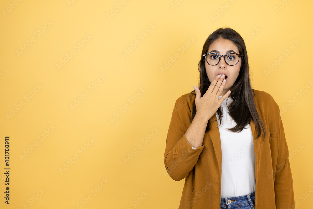 Young beautiful woman wearing a blazer over isolated yellow background Pretty blonde woman with long hair standing over yellow background surprised covering the mouth Young beautiful woman wearing a blazer over isolated yellow background Pretty blonde woman with long hair standing over yellow background surprised covering the mouth