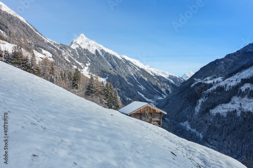 Berghütte mit verschneitem Berggipfel im Hintergrund