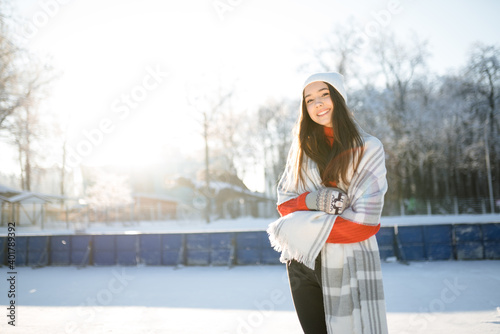 Caucasian girl in a white hat is skating on a frozen river in a snowy park