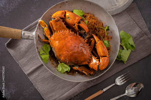 Baked fresh sea crab with vermicelli or glass noodle in the cook pot with table set up ready to eat. Black background