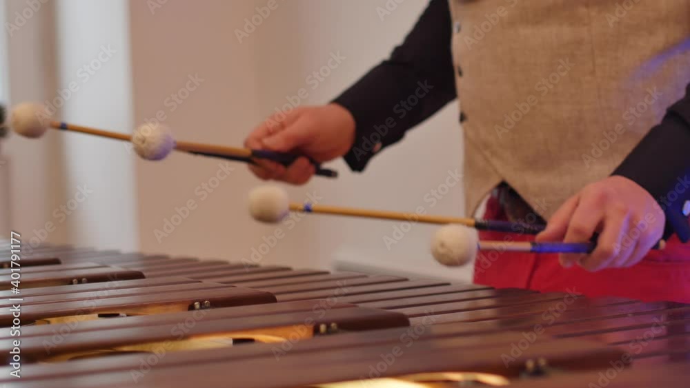 Close of a marimba played by the percussion section of band. male hands playing balafon ethnic musical instrument motion front view close up. Man holding sticks for marimba music. 
