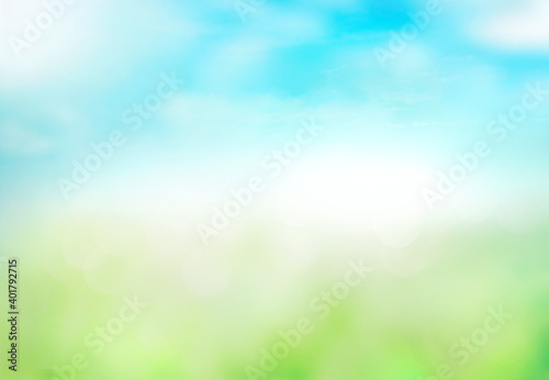 Green grass blue sky blurred bokeh background.Abstract spring summer nature backdrop,de focused illustration. © nys